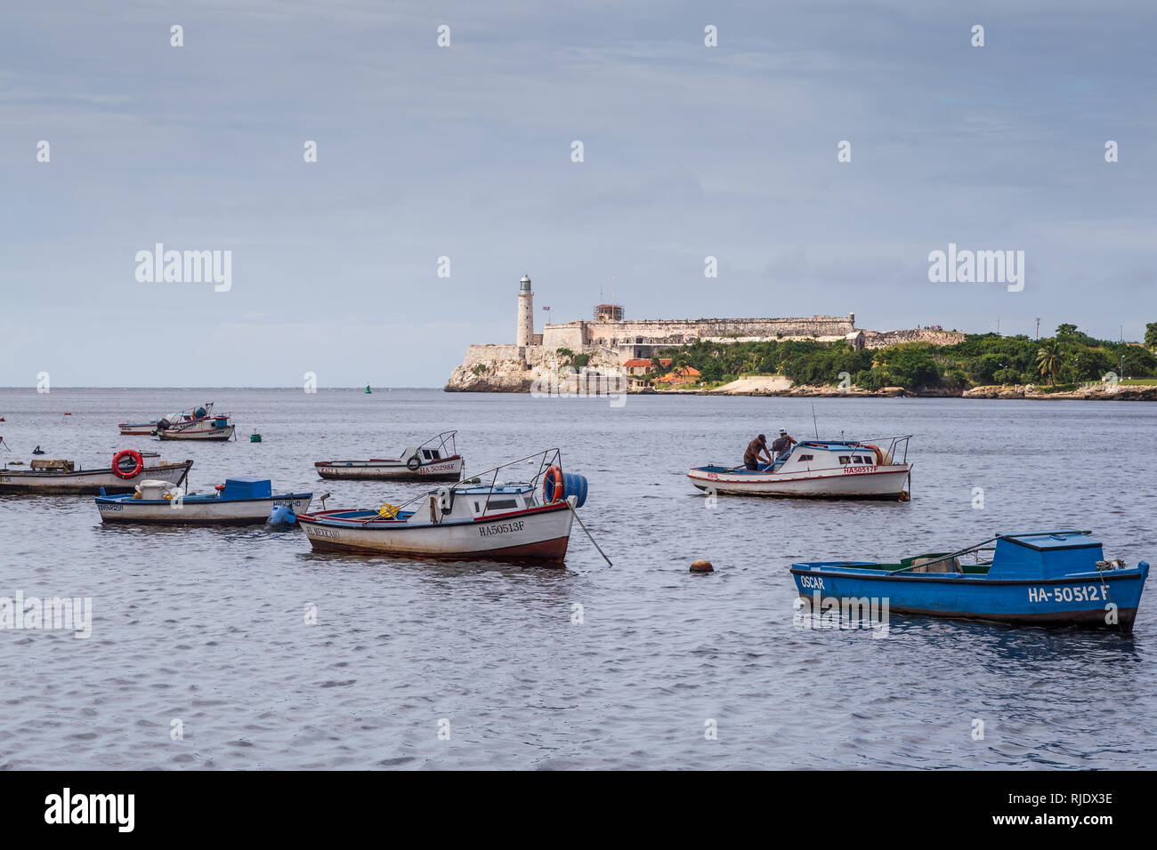 Vista al fisher barche con due pescatori e Morro Castle Lighthouse ( Castillo de los Tres Reyes del Morro ) attraverso la Baia dell Avana a Cuba Foto Stock