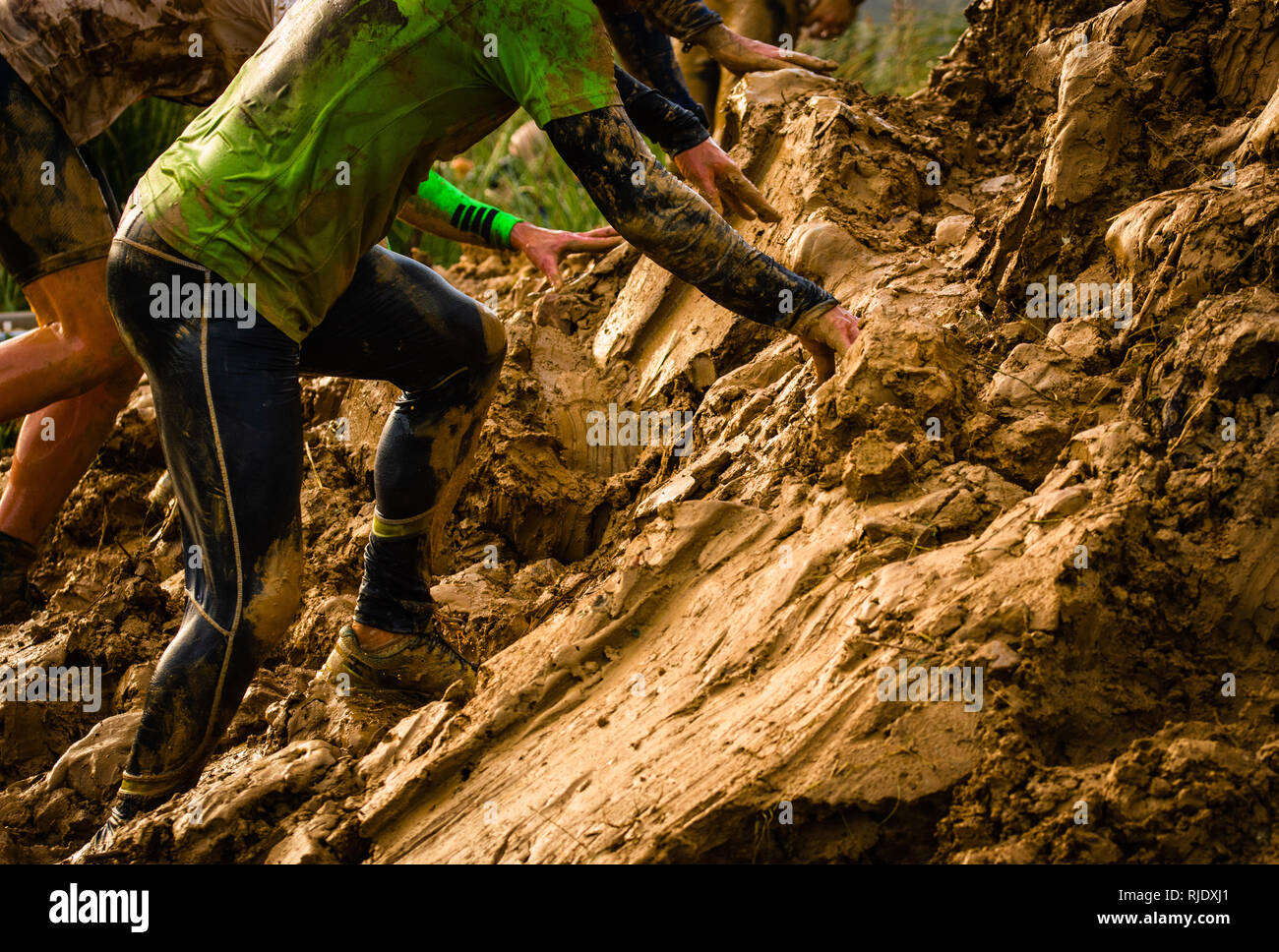 Ostacolo fangoso gara runner in azione. Esecuzione di fango Foto Stock