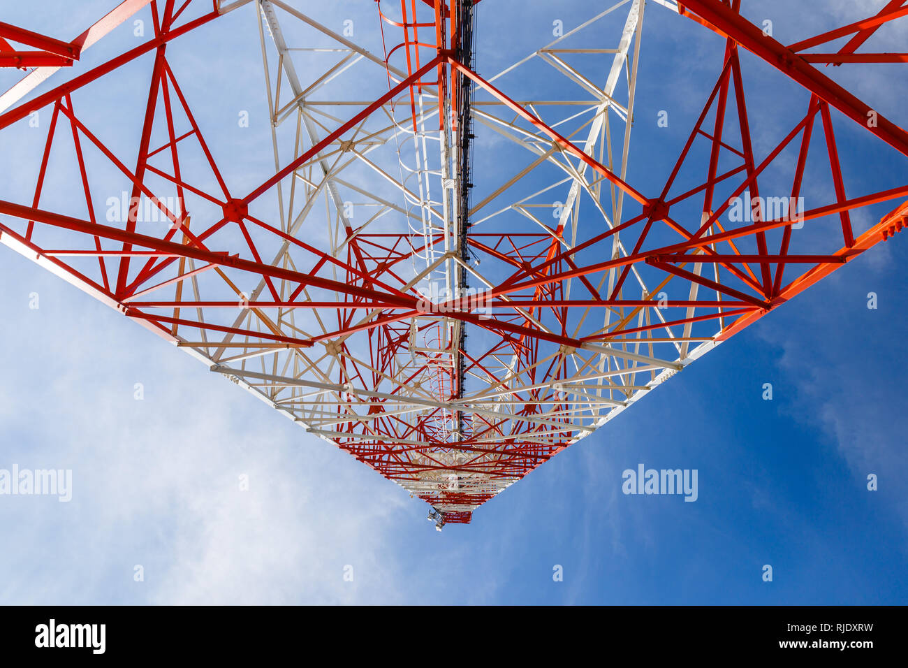 Vista dal basso di una torre per telecomunicazioni. rosso e bianco cellulare torre contro il cielo blu, vista dal basso Foto Stock