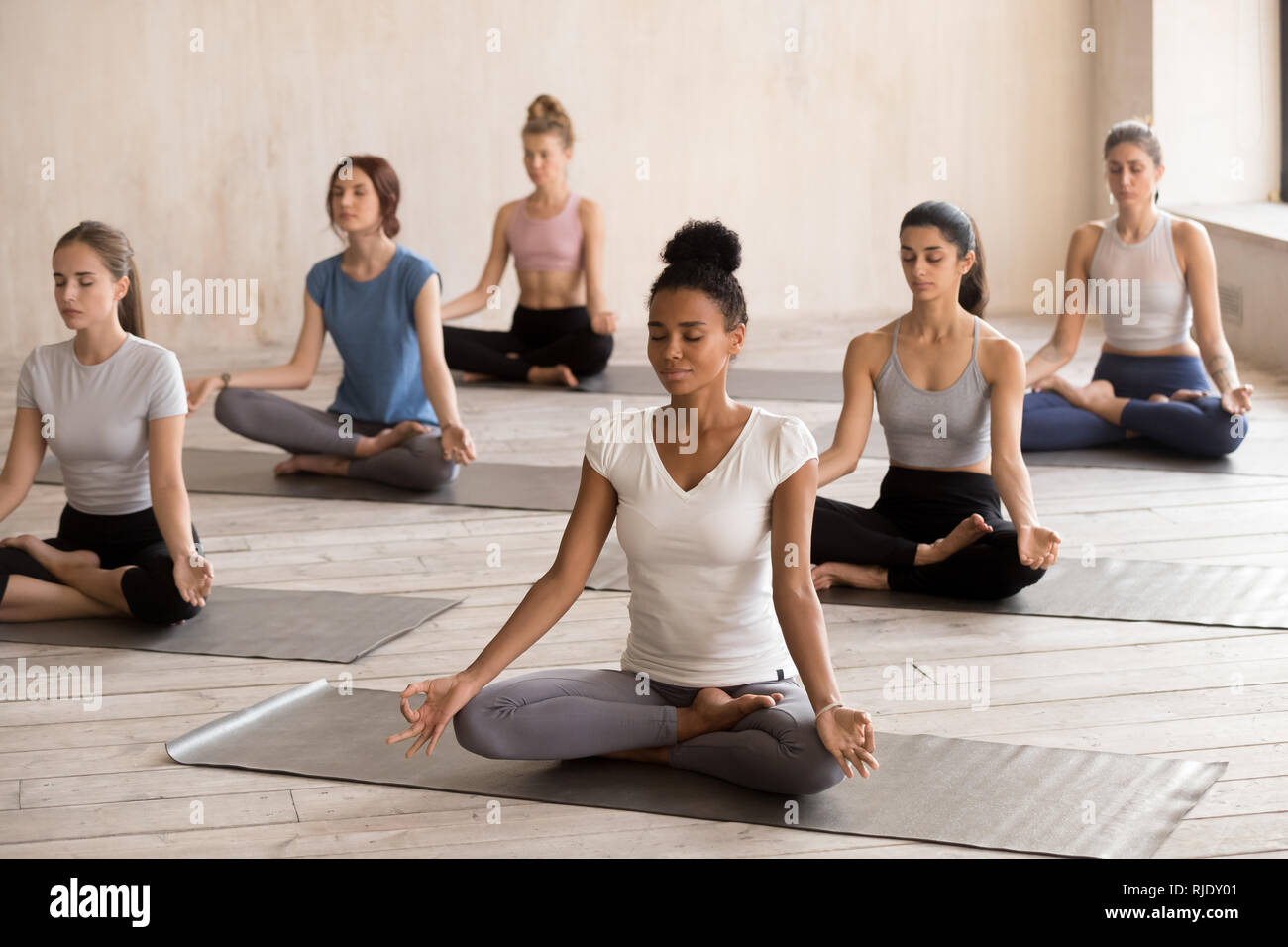 Diverse calma yogi femmina meditare nella posizione del loto insieme Foto Stock