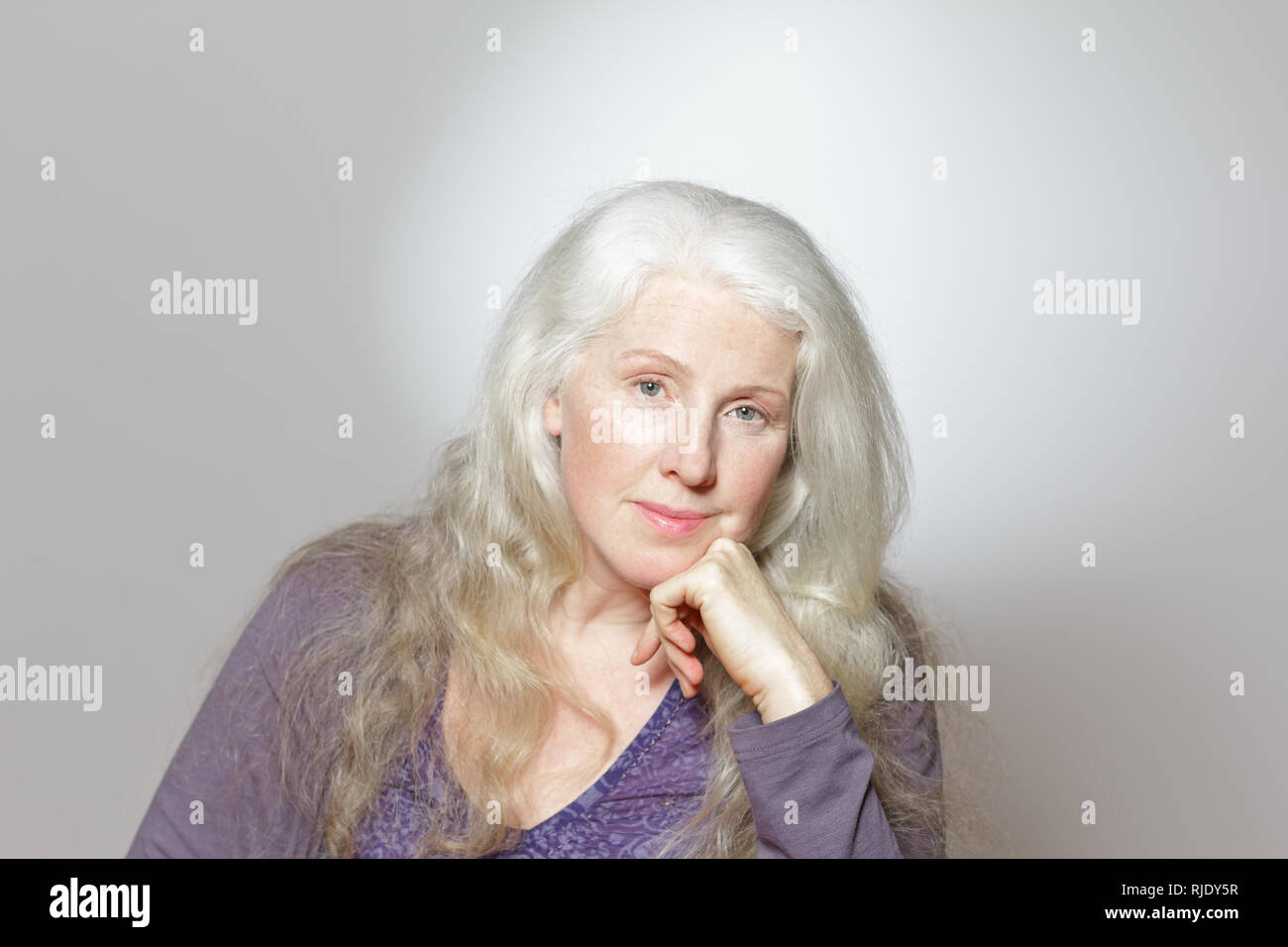 Colpo di Testa di una donna matura con splendidi ricci lunghi capelli grigi davanti a uno sfondo bianco, copia dello spazio. Foto Stock