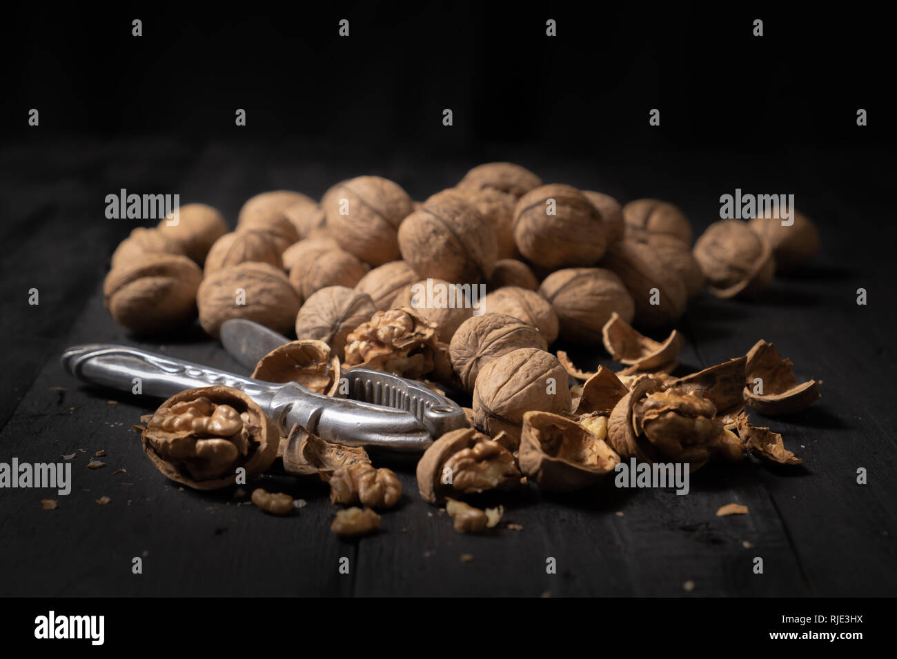 Noci su sfondo scuro. Basso-chiave immagine di dadi su nero tavolo rustico, luce artistica e tecnica di ombreggiatura Foto Stock