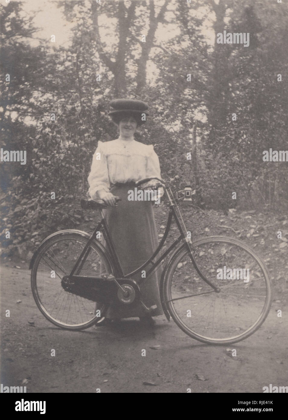 Vintage Edwardian Cartolina fotografica di un vestito elegantemente Lady tenendo un ciclo di pedale. Foto Stock