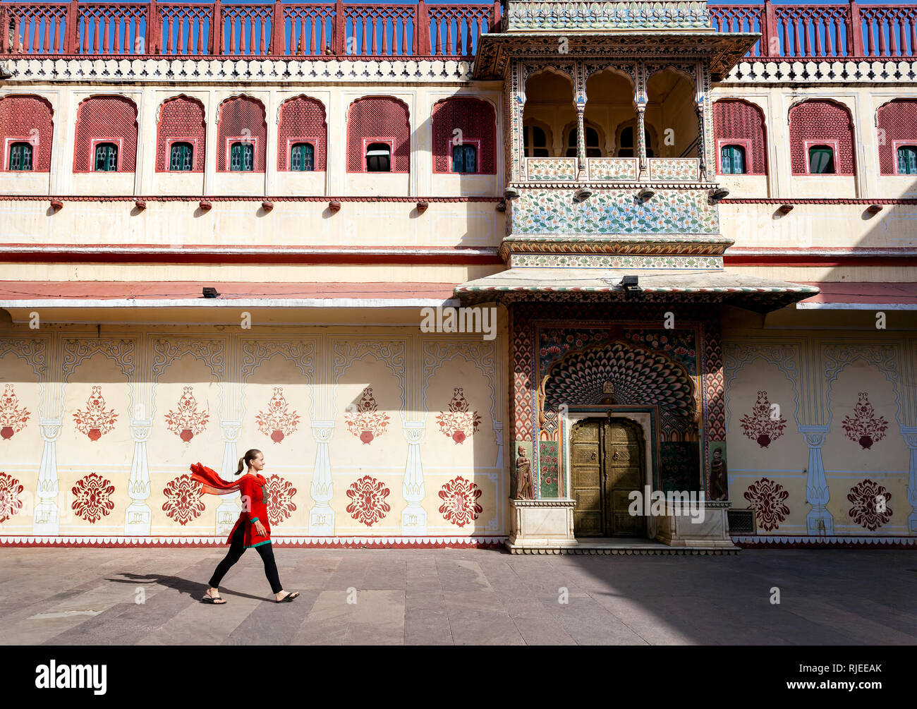 La donna in sciarpa rossa a piedi di piazza nel palazzo di città di Jaipur, Rajasthan, India Foto Stock