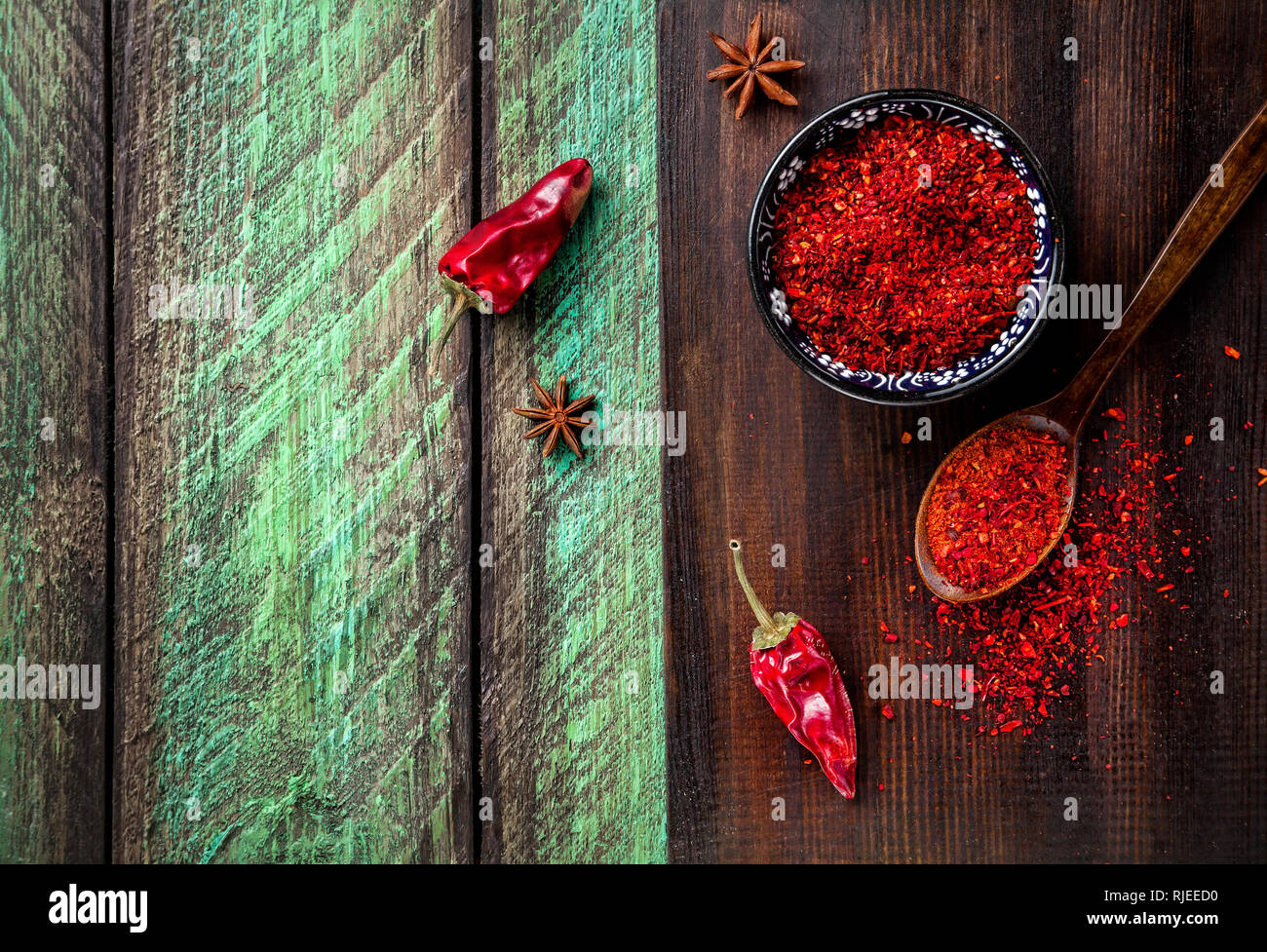 Red Chil pepperi e la paprica in polvere sul buio tagliere in legno verde tabella Foto Stock