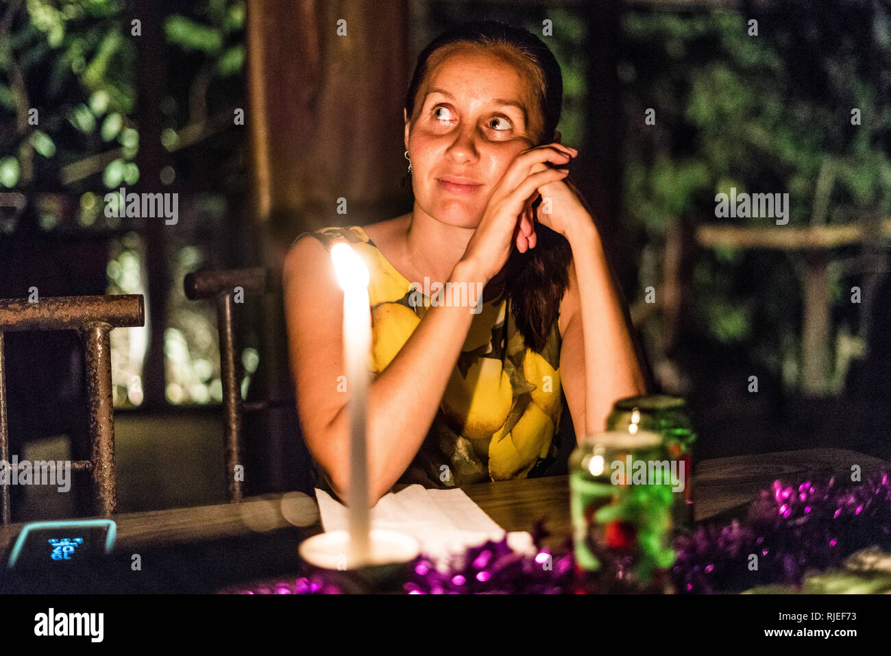 Un ritratto di una donna bellissima fantasticando a lume di candela durante una romantica cena presso un ristorante locale in una foresta pluviale tropicale del Costa Rica Foto Stock