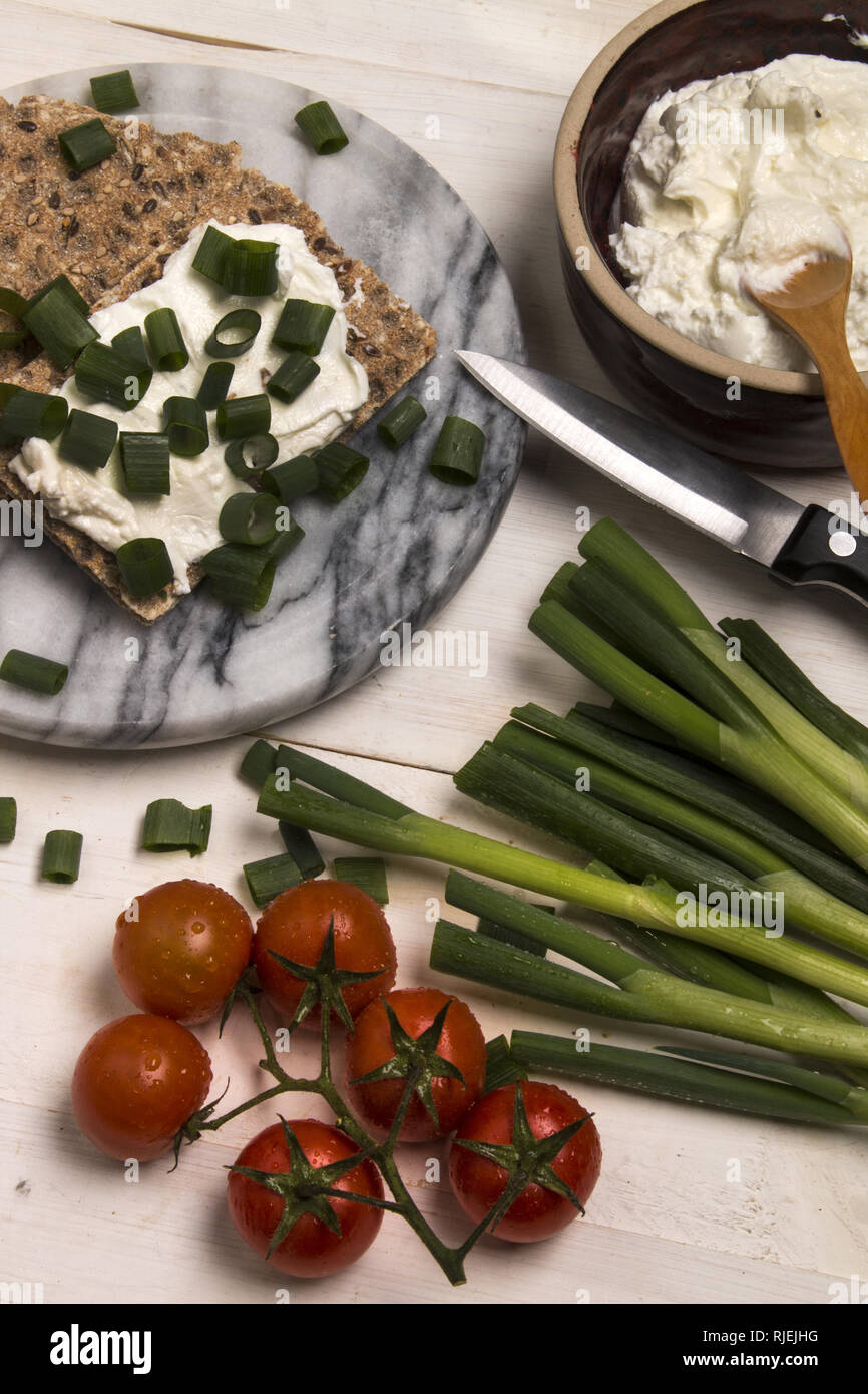 Un sano, vegetariane prima colazione con pane croccante detto Knäckebrot, quark e fresche cipollina sul marmo Foto Stock