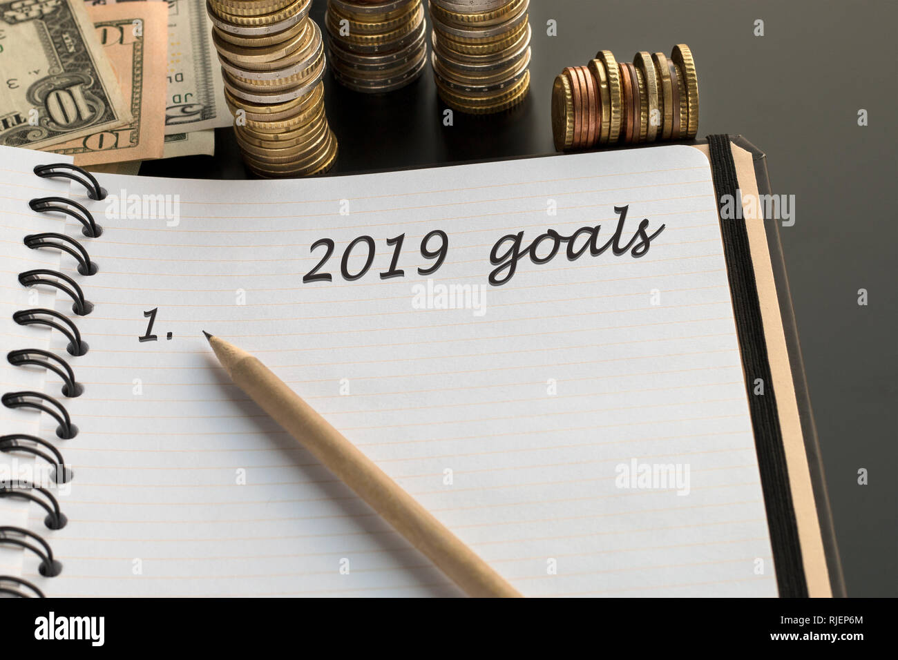 Blocco note con 2019 testo obiettivi, matita, denaro sfondo. Argomento di sogni, obiettivi, piani Foto Stock