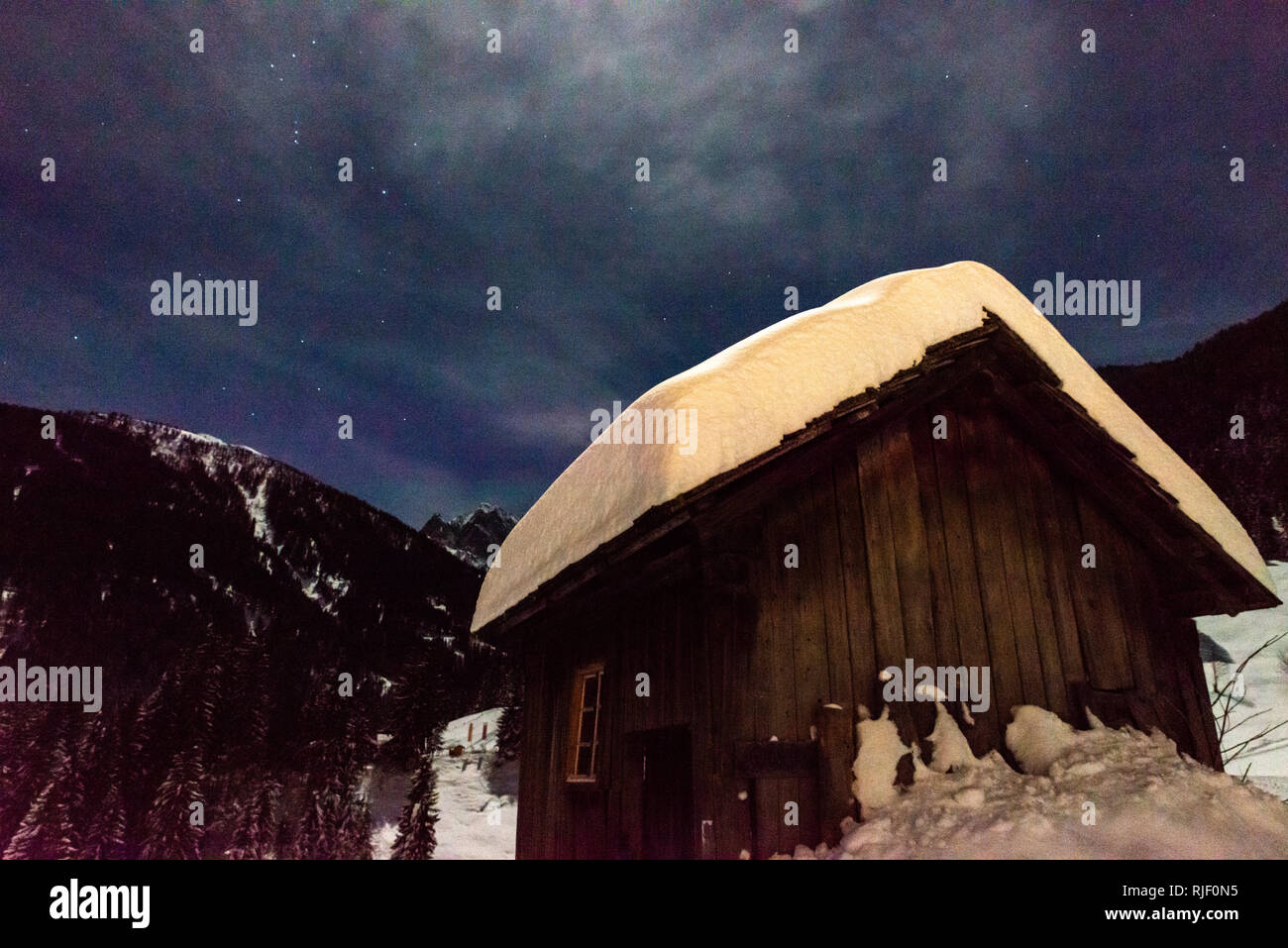 Cabina nelle Alpi coperte di neve durante la notte Foto Stock