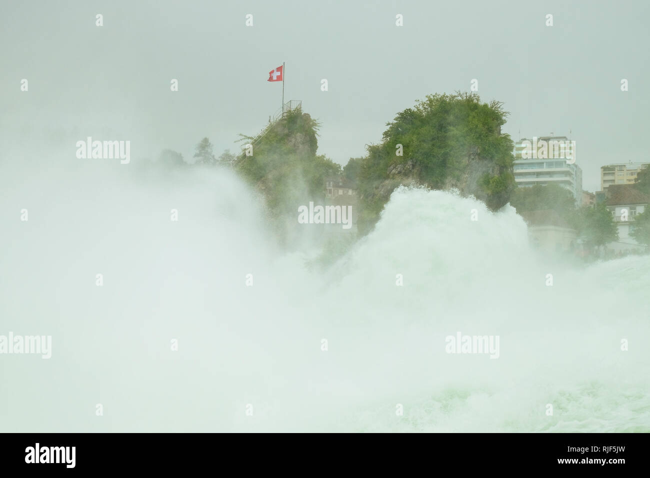 Un fragore cascata ed una piccola roccia con la bandiera svizzera Foto Stock