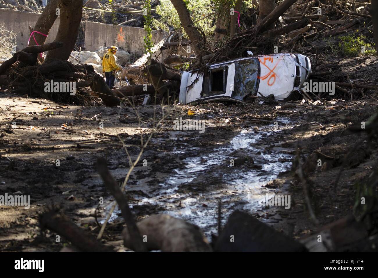 Un auto è ribaltata e un quartiere superamento con fango come primi responder e soldati da la 315costruzione verticale Company, California Esercito Nazionale Guardia, opera al fine di rimuovere i detriti, gen. 13, 2018 a Montecito, California. Il gruppo ha lavorato per scavare nelle case e strade a seguito di una frana di fango devastanti Gen 9 che ha ucciso almeno 20 persone, case distrutte e quartieri di sinistra tagliata. Foto Stock