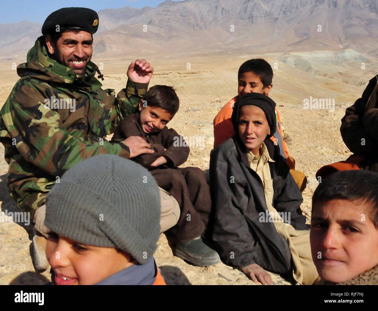 KABUL, Afghanistan -- un esercito nazionale afghano soldato fornendo sicurezza per un vivere incendio campo si siede con i bambini dalla zona circostante mentre prendendo una breve pausa durante il corso di formazione. Spesso i bambini curiosi venite a vedere i soldati treno su intervalli aperti nella periferia della città di Kabul. Foto Stock