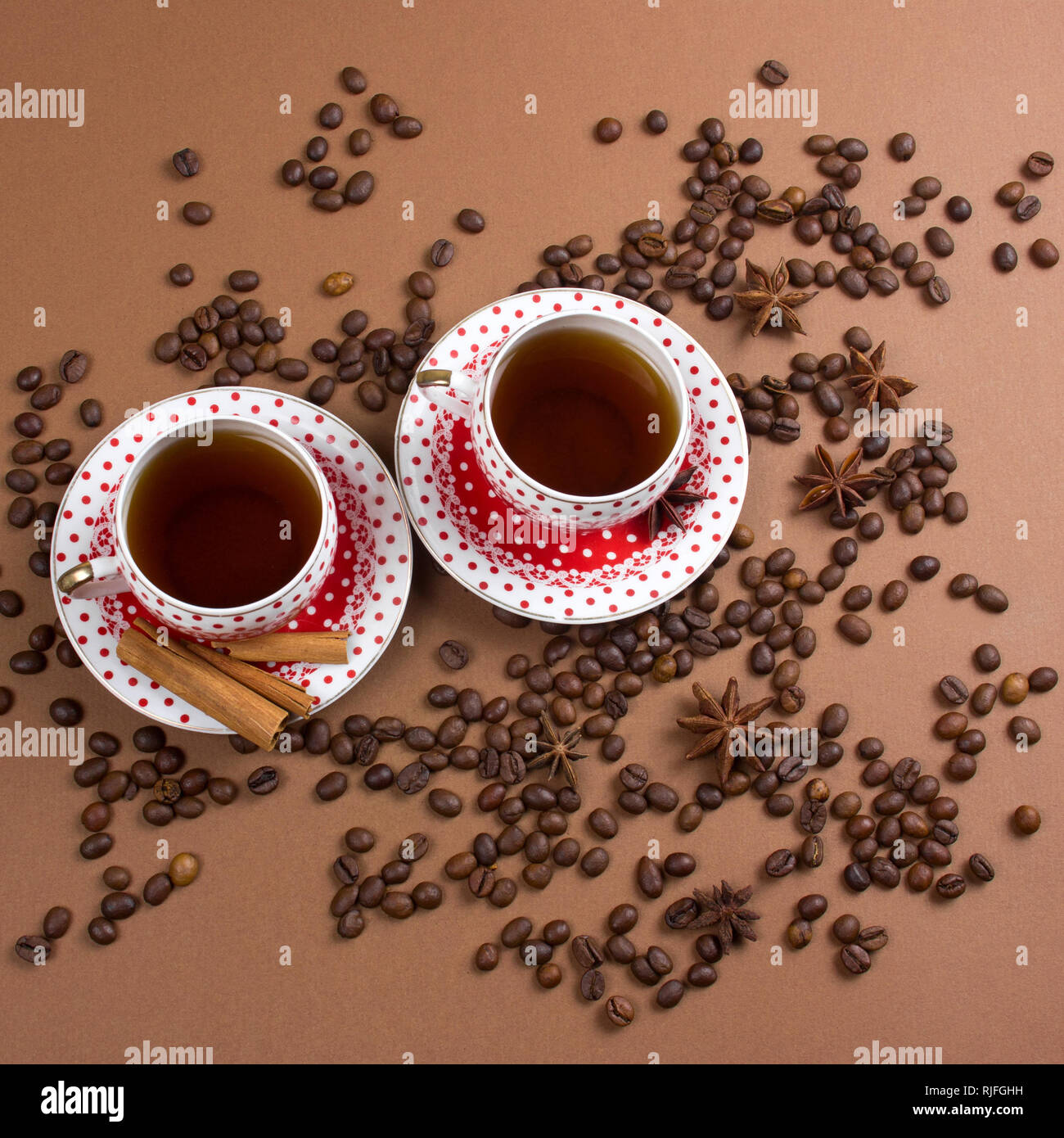 Due piccante di caffè nero polka dot tazze e i chicchi di caffè pasticcio su sfondo marrone squae immagine Foto Stock