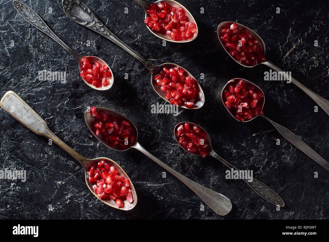 Lay piatto con cucchiai di metallo e semi di granato Foto Stock