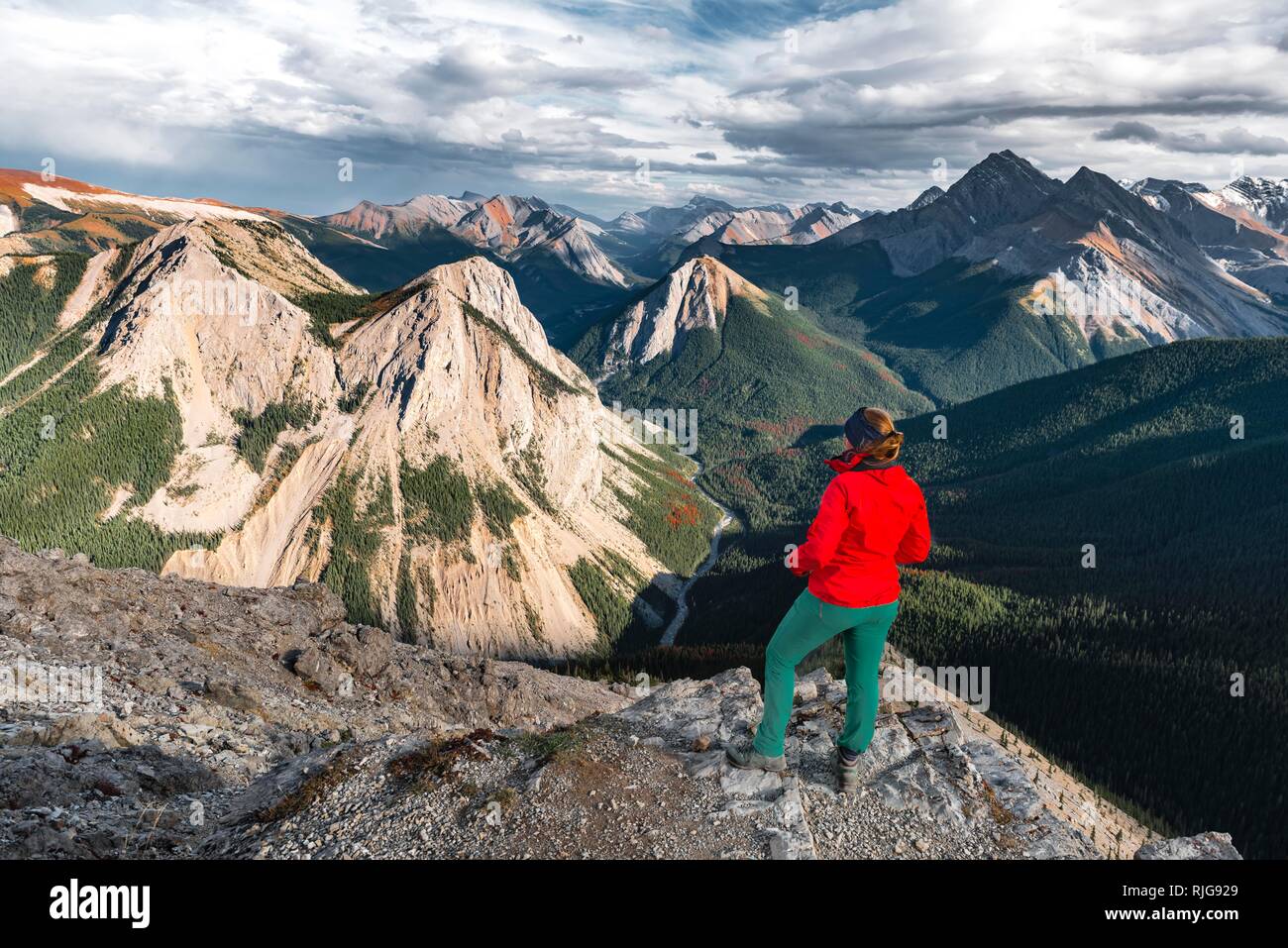Escursionista femmina guarda dal vertice oltre il paesaggio di montagna, vertice con orange depositi di zolfo, Vista panoramica Foto Stock