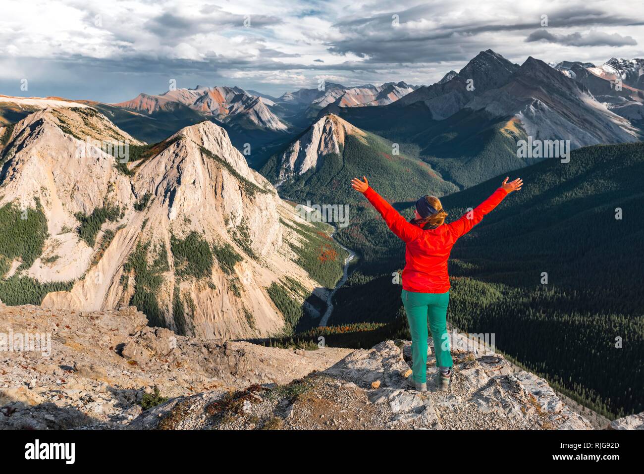 Escursionista femmina con i bracci sollevati cercando di vertice oltre il paesaggio di montagna, vertice con orange depositi di zolfo, Vista panoramica Foto Stock