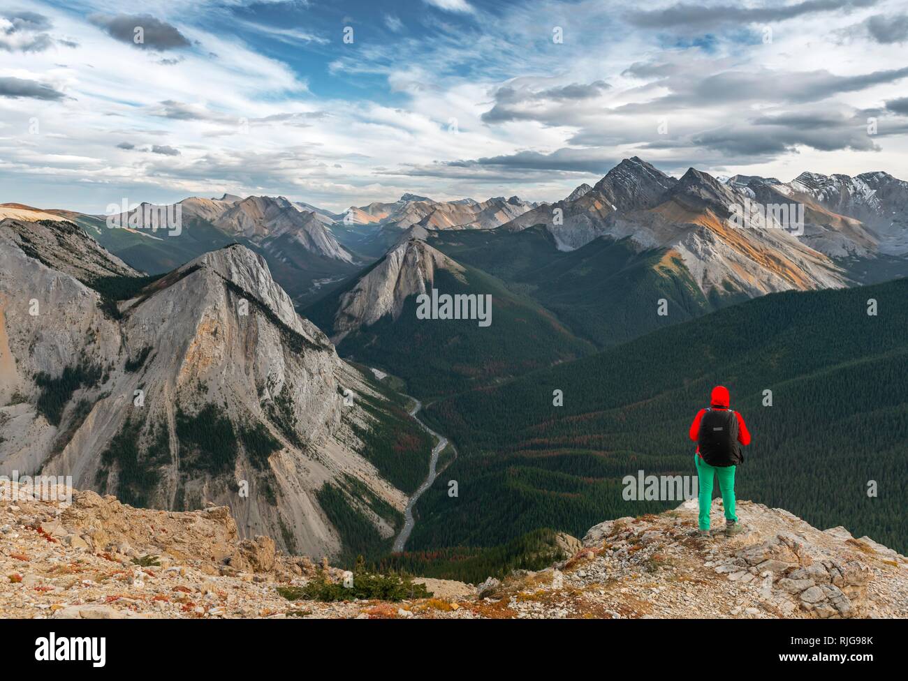 Escursionista femmina guarda dal vertice oltre il paesaggio di montagna, vertice con orange depositi di zolfo, Vista panoramica Foto Stock
