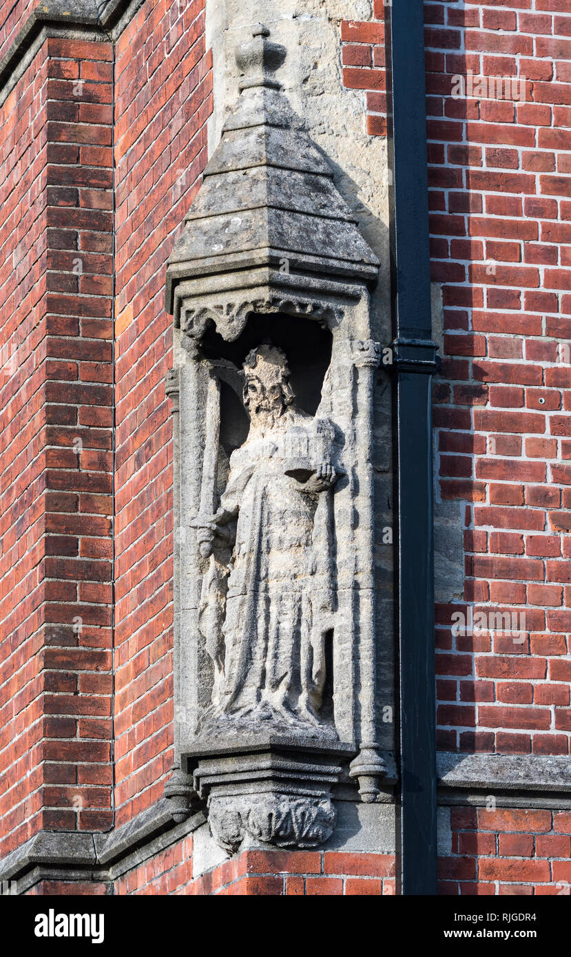 Epoca medievale storica statua di pietra in un'edicola su un angolo di un edificio di mattoni rossi, guardando molto spiovente e consumata in Arundel, West Sussex, Regno Unito. Foto Stock