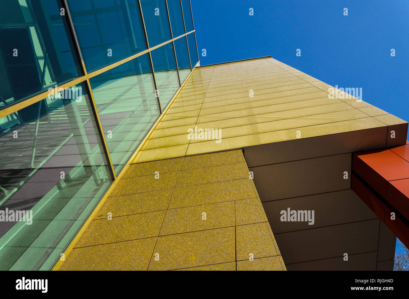Forme geometriche di un moderno edificio di vetro e pietra contro il cielo blu chiaro Foto Stock