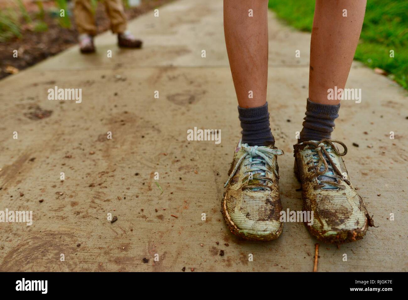 Scarpe fangose su giovani bambini in età scolare dopo aver camminato lungo una pista sterrata, Moongun sentiero a piedi a molle di Elliot, Townsville, Queensland, Australia Foto Stock