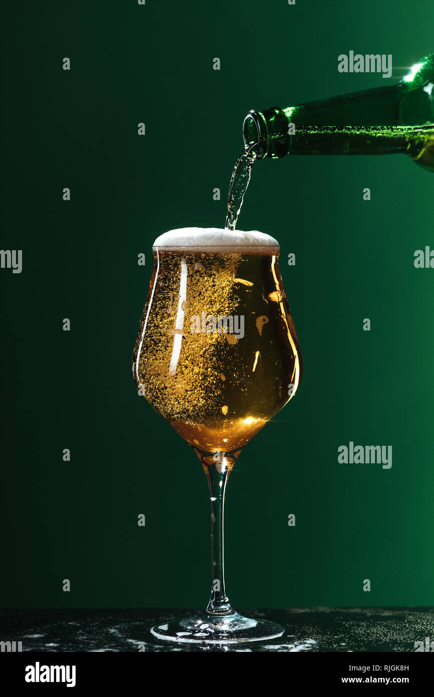 Versare la birra in vetro isolato sul verde, san Patrizio giorno concept Foto Stock