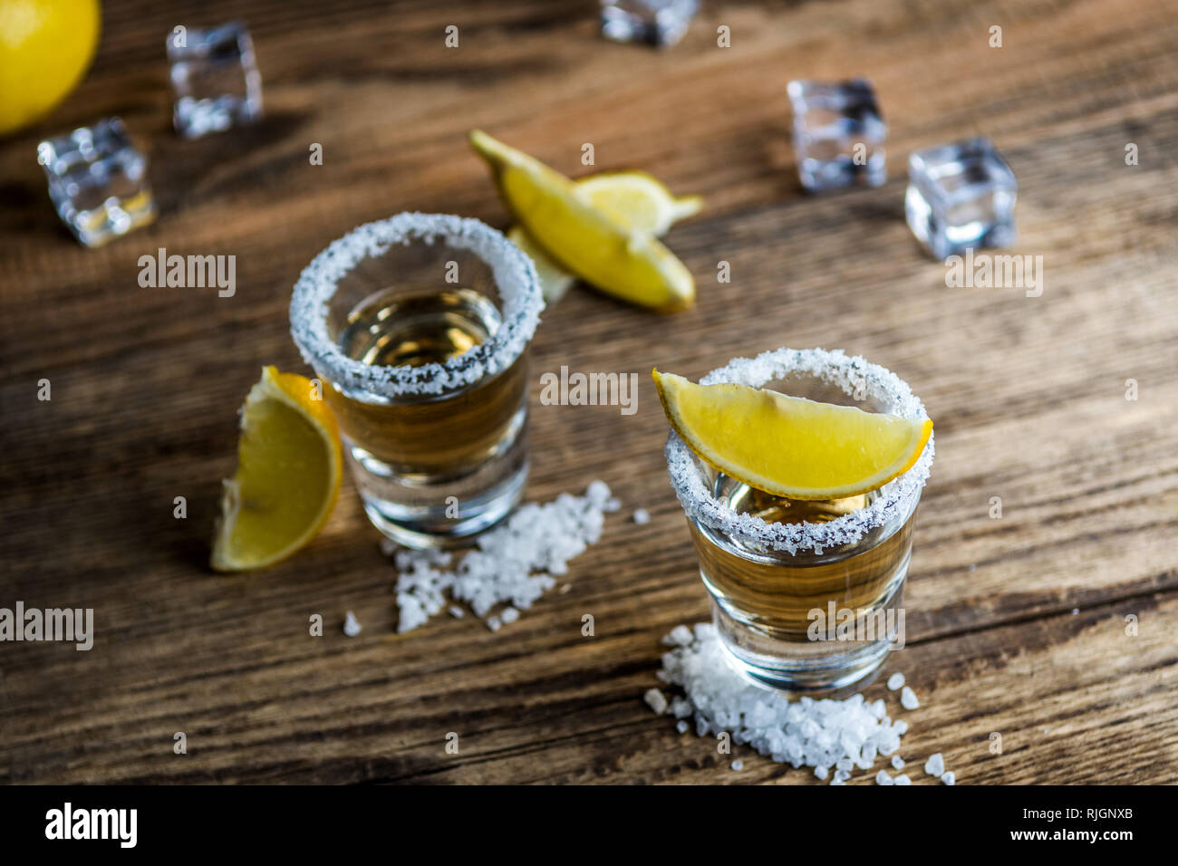 Tradizionale messicano alcool bere la tequila con limone e sale e cubo di ghiaccio sul tavolo di legno Foto Stock