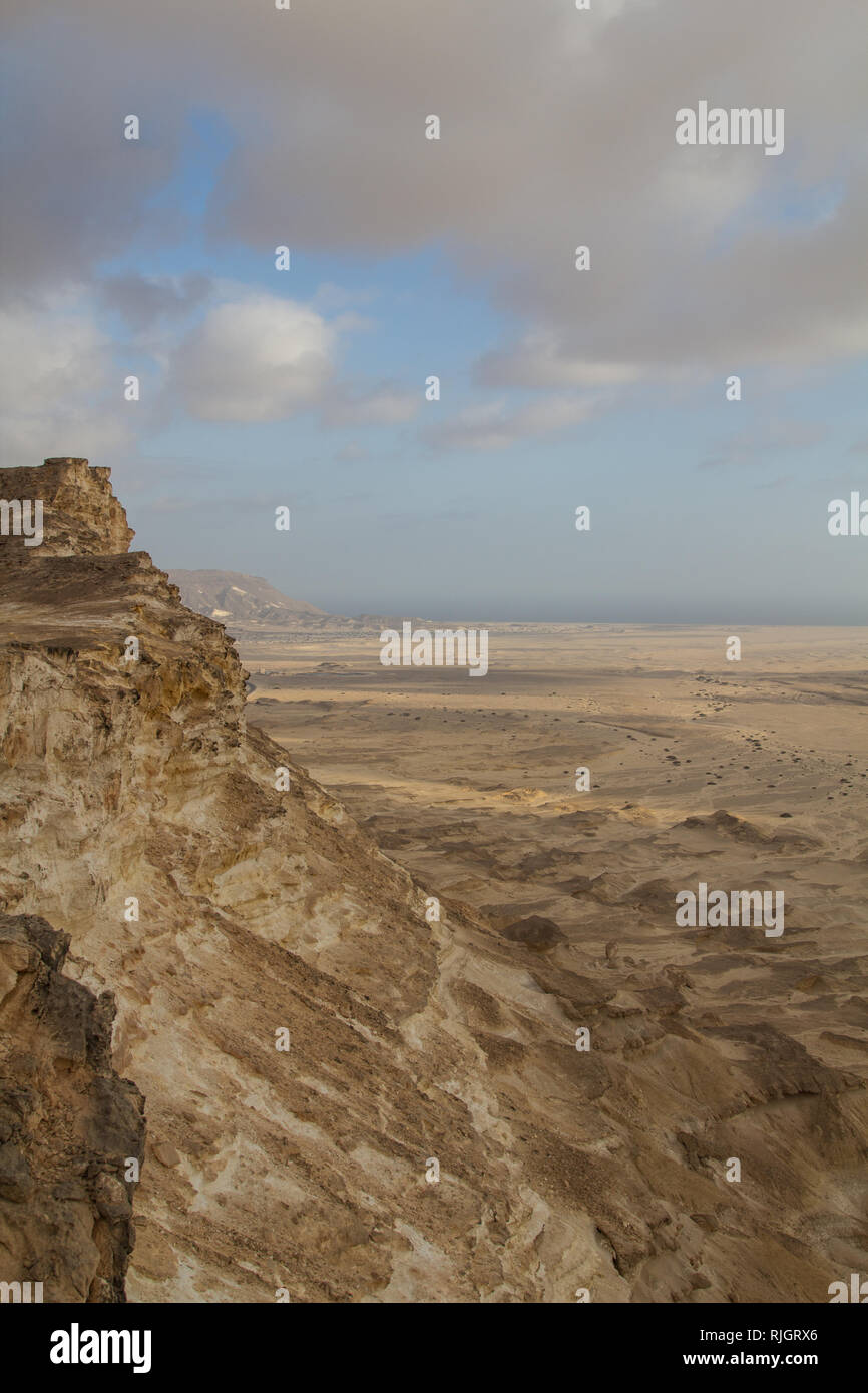 Ripide scogliere e drammatici nuvole sopra un semplice dal punto di vista di un altopiano vicino al litorale nel Sultanato di Oman Foto Stock