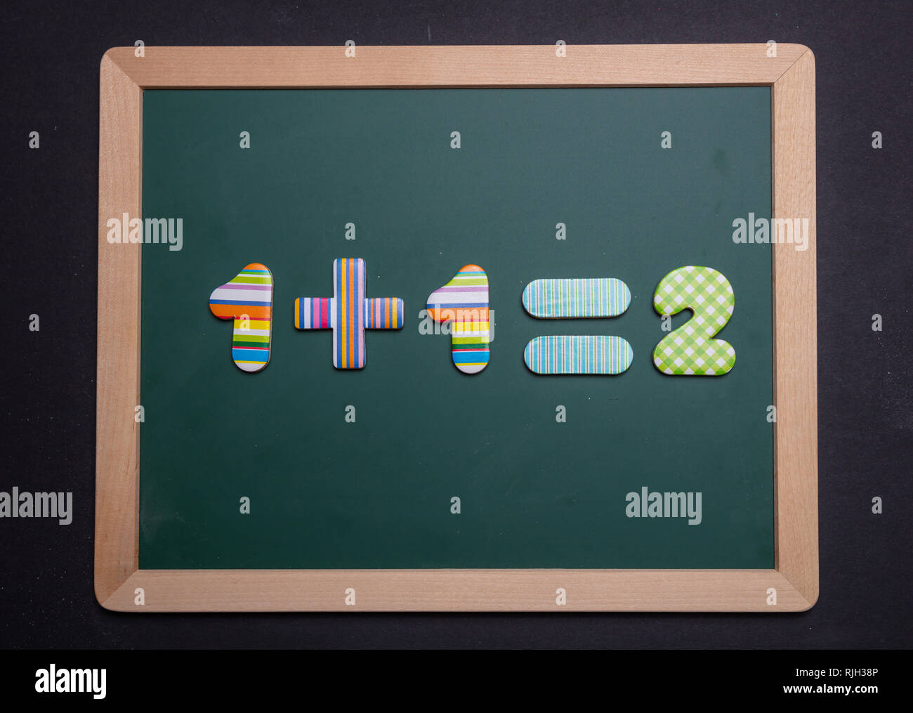 Math addizione semplice equazione sulla scheda verde con telaio in legno, sfondo nero Foto Stock