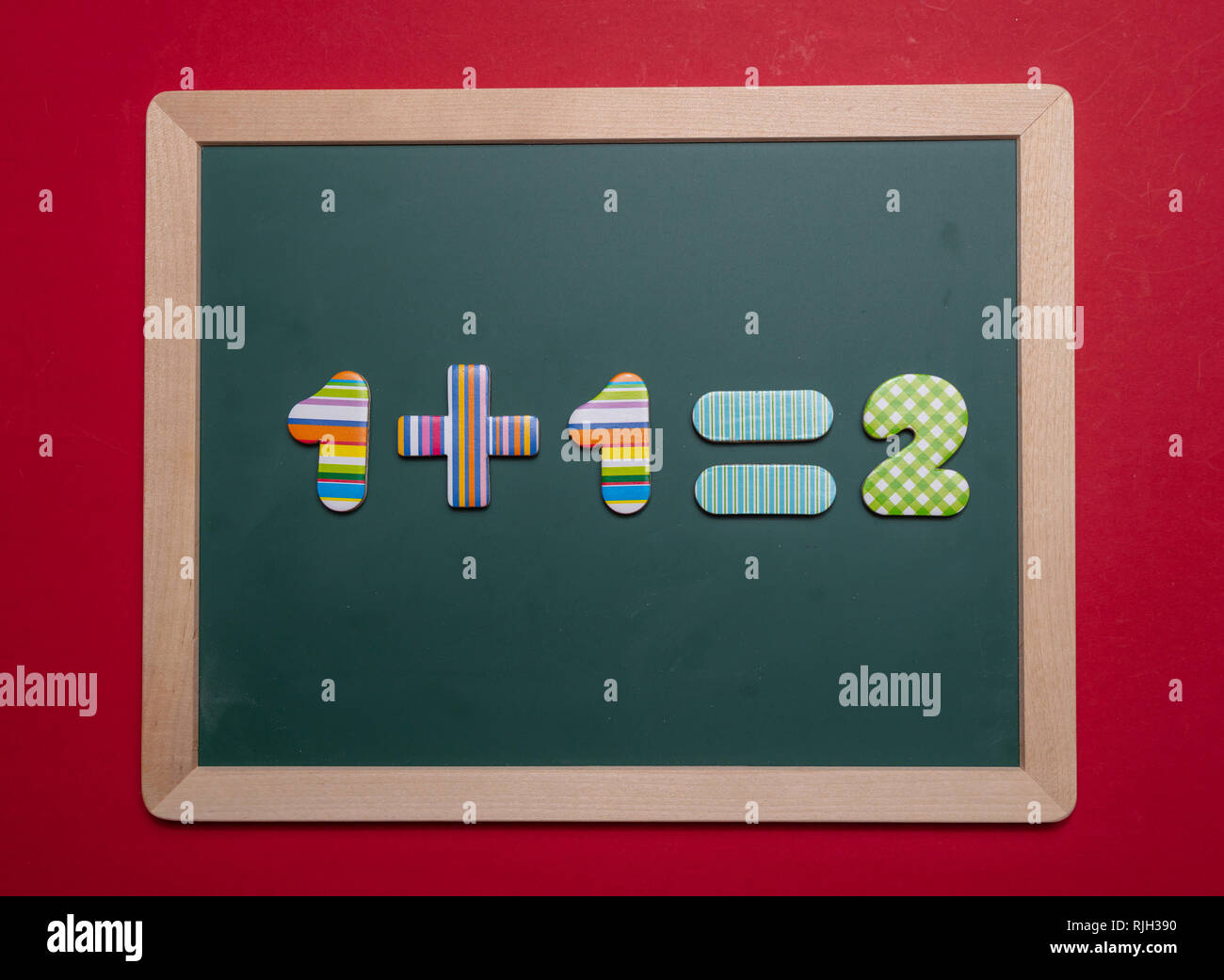 Math addizione semplice equazione sulla scheda verde con telaio in legno, sfondo rosso Foto Stock