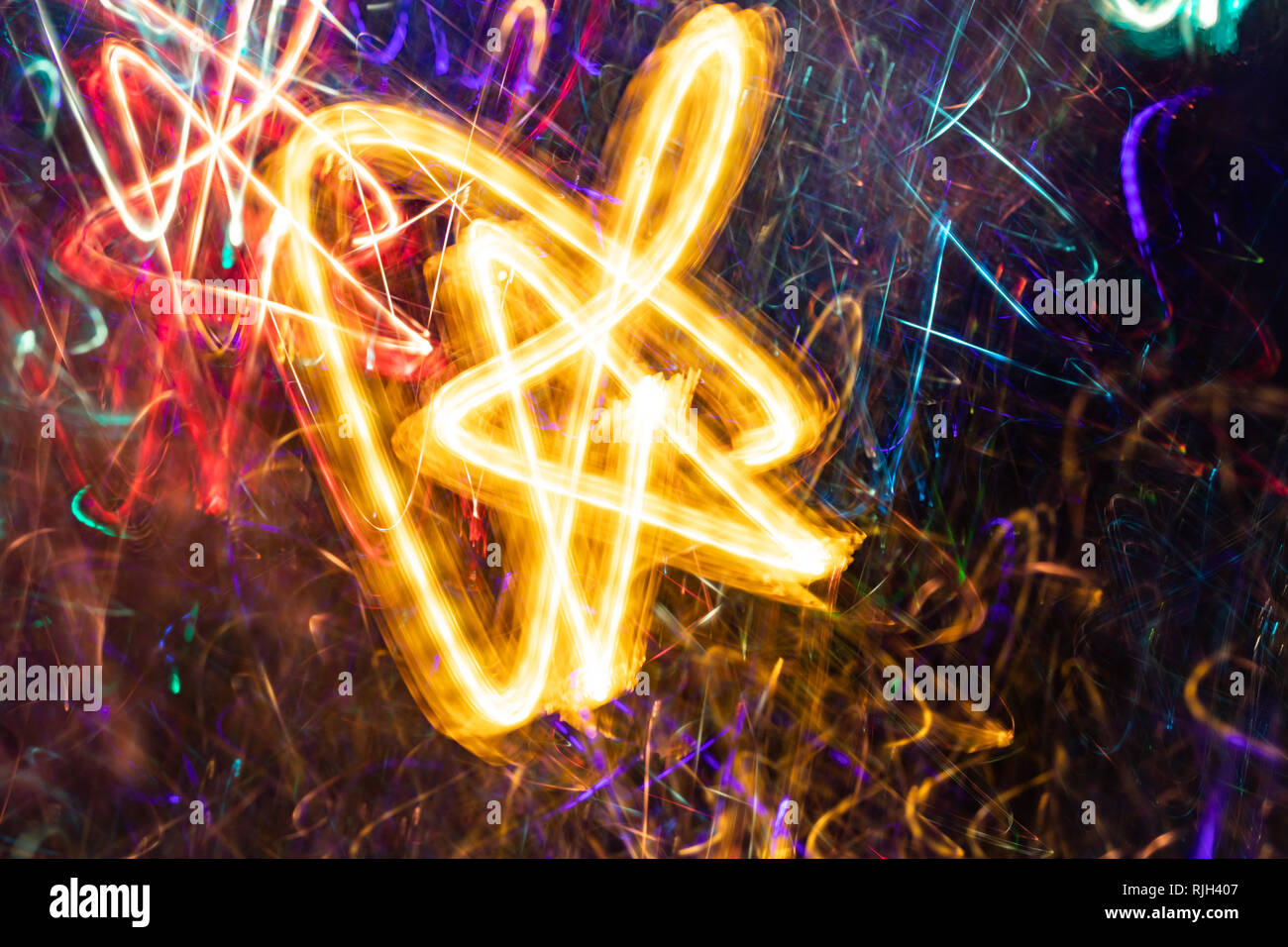 Giallo brillante fiorire di luce a forma di stella sul multicolore sfondo incandescente. Abstract background. Effetto fotografico con una lunga esposizione. Foto Stock