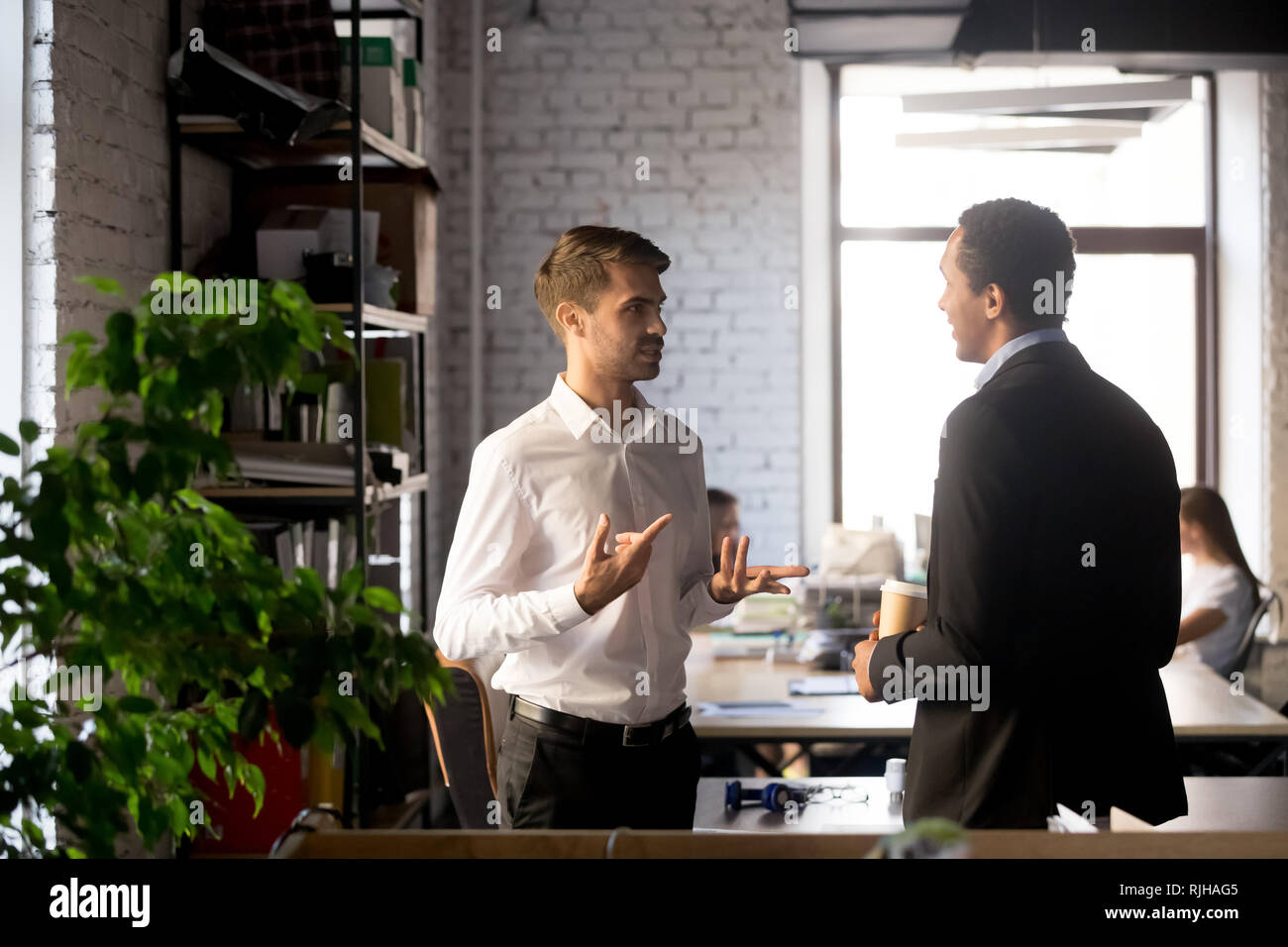 I colleghi aventi permanente di conversazione informale in office Foto Stock