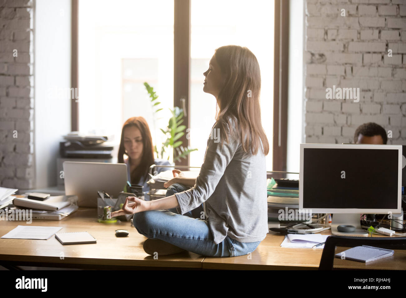 Calma lavoratore di sesso femminile che medita sulla scrivania in ufficio Foto Stock