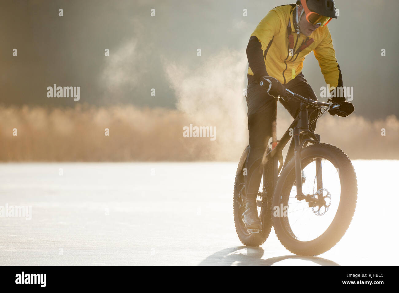 Uomo in bicicletta su un lago ghiacciato Foto Stock