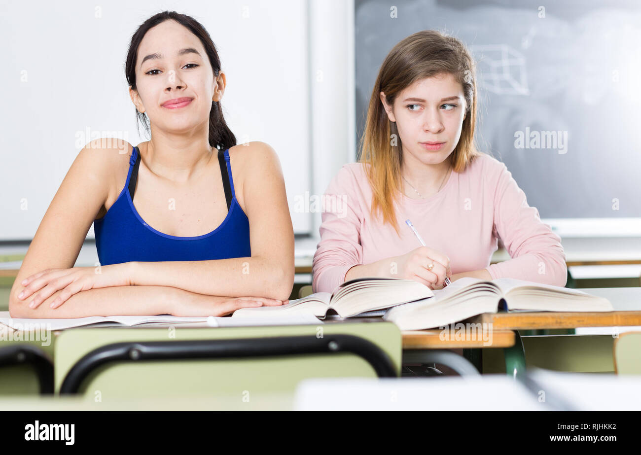 Giovane ragazza sta pensando di successo la sua ragazza al banco della classe. Foto Stock