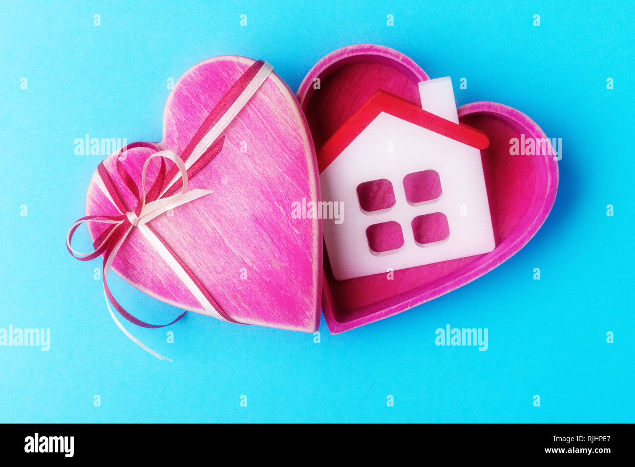 A forma di cuore scatola regalo con modello di casa su sfondo blu Foto Stock