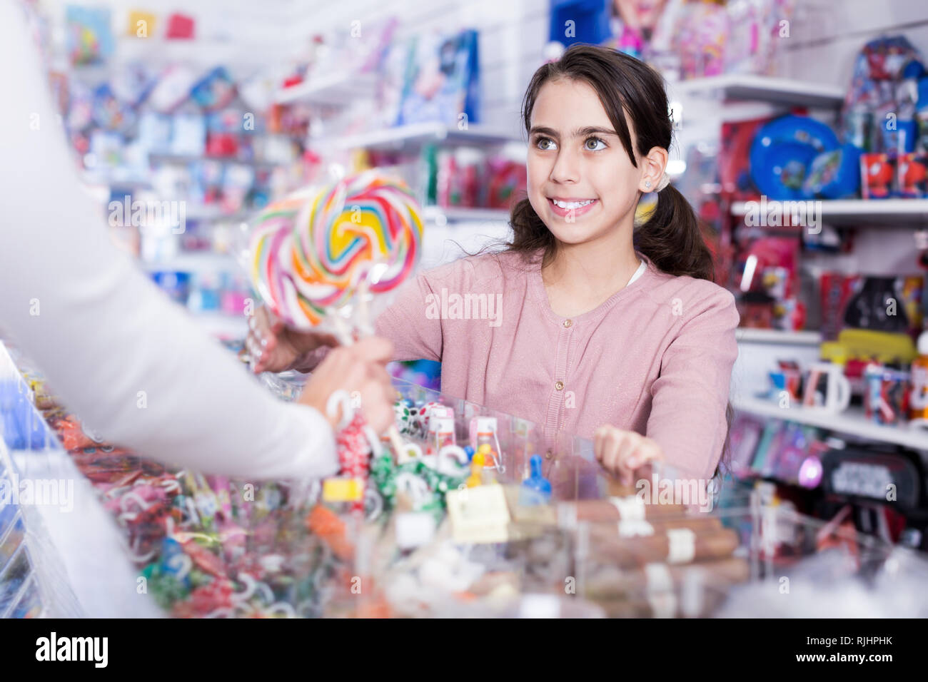 Positivo piccola ragazza acquistare dolciumi dal venditore nel negozio di dolciumi Foto Stock