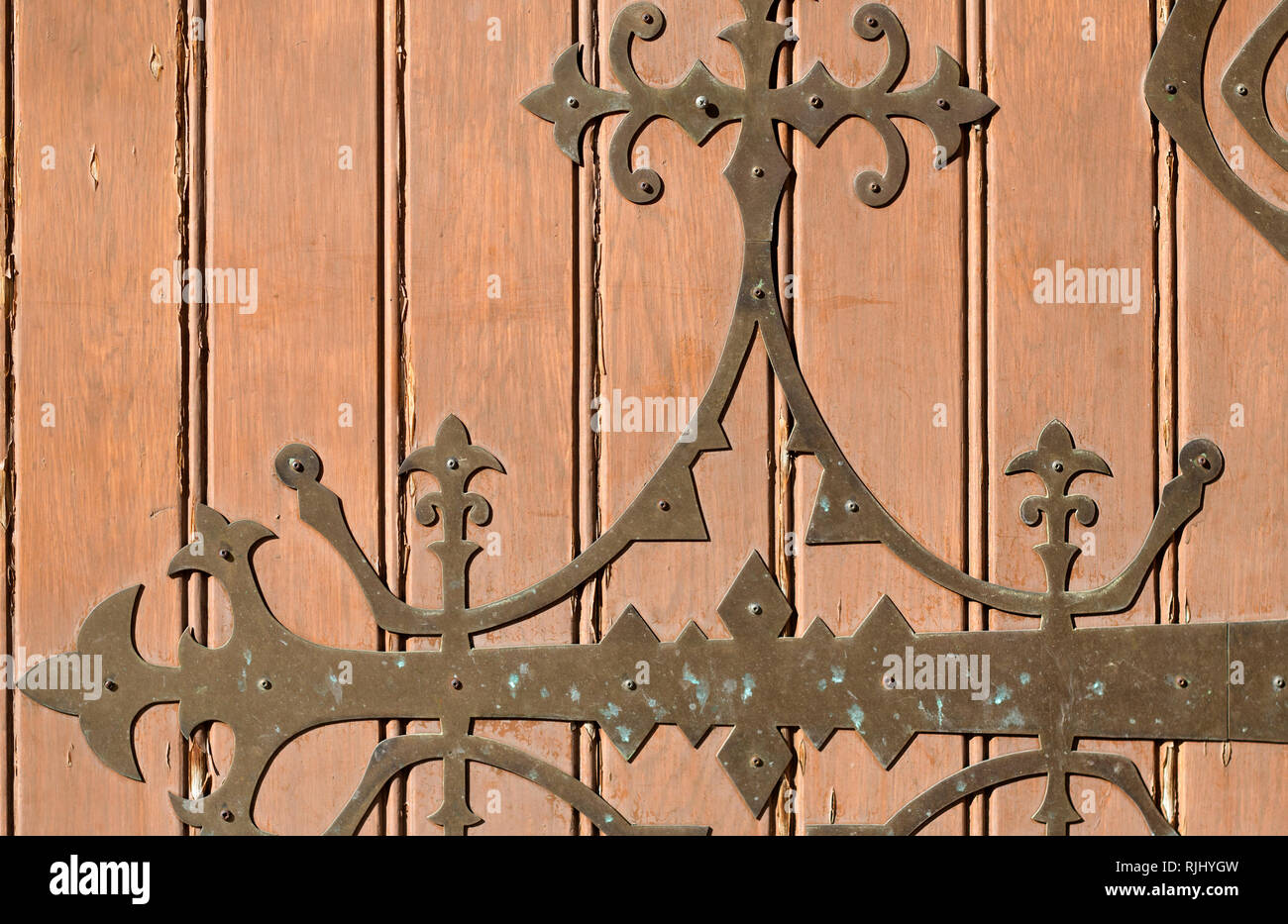 Luce marrone porta in legno con metallo forgiato il motivo di un vecchio tempio nella giornata di sole Foto Stock