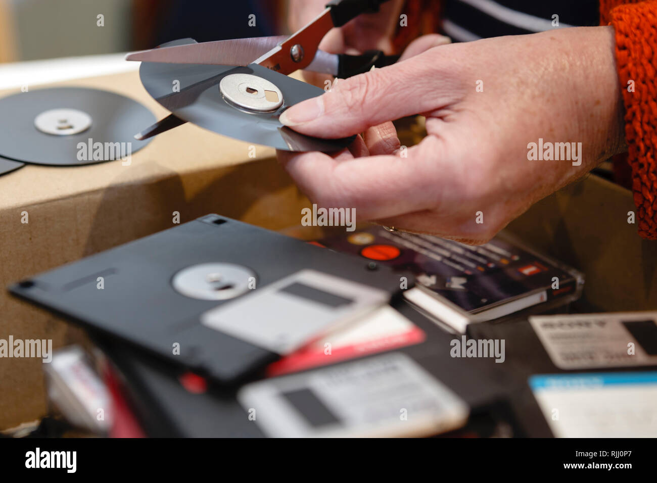 Taglio fino vecchio floppy disc con le forbici per distruggere le informazioni Foto Stock