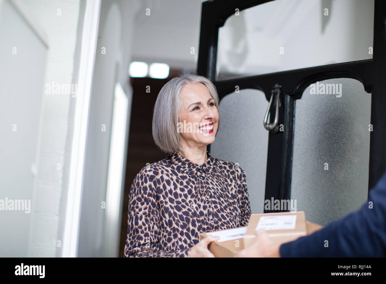 Donna matura la ricezione di una consegna a domicilio Foto Stock