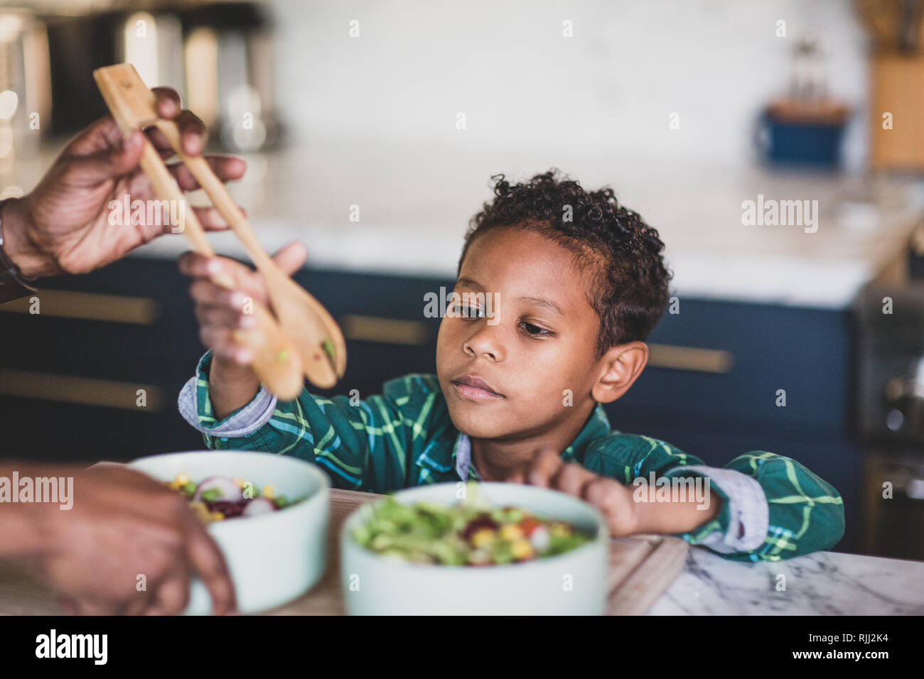 African American boy aiutando padre preparare pasti sani in cucina Foto Stock