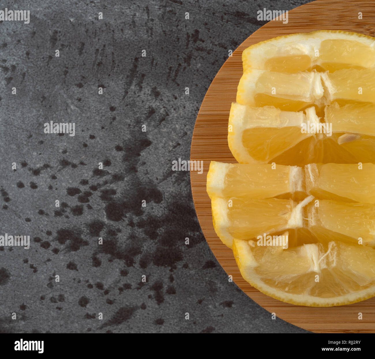 Vista superiore di diverse fette di limone su un legno tagliere in cima a un contatore Gray top. Foto Stock