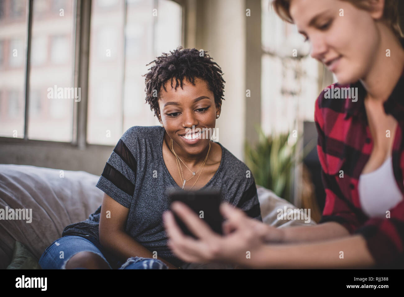 Giovani amici adulti socializzare mentre sui loro smartphone Foto Stock