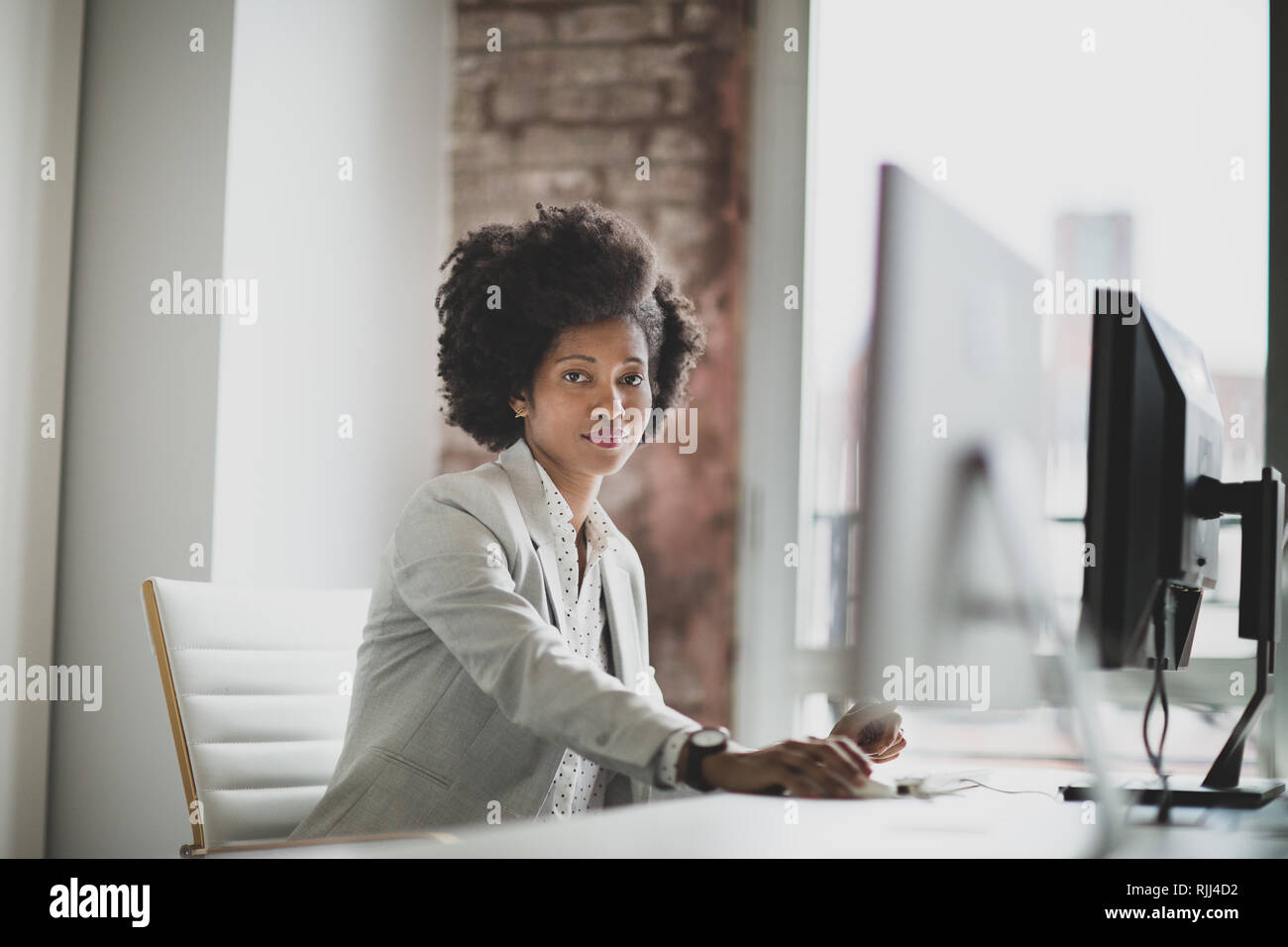 Ritratto di una donna africana di american business executive lavora in un ufficio su un computer desktop Foto Stock