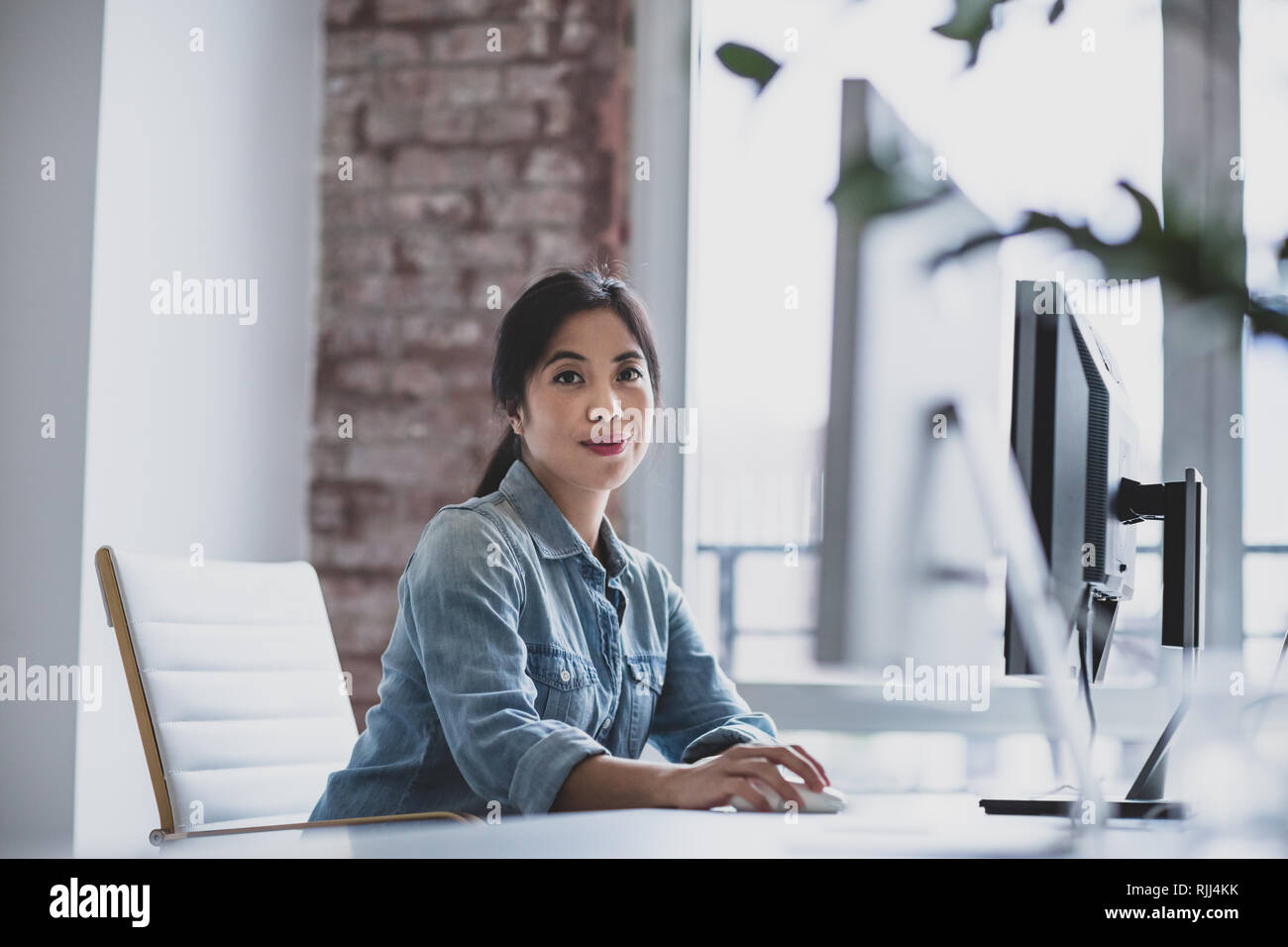 Ritratto di una giovane donna adulta di dirigenti che lavorano in un ufficio su un computer desktop Foto Stock