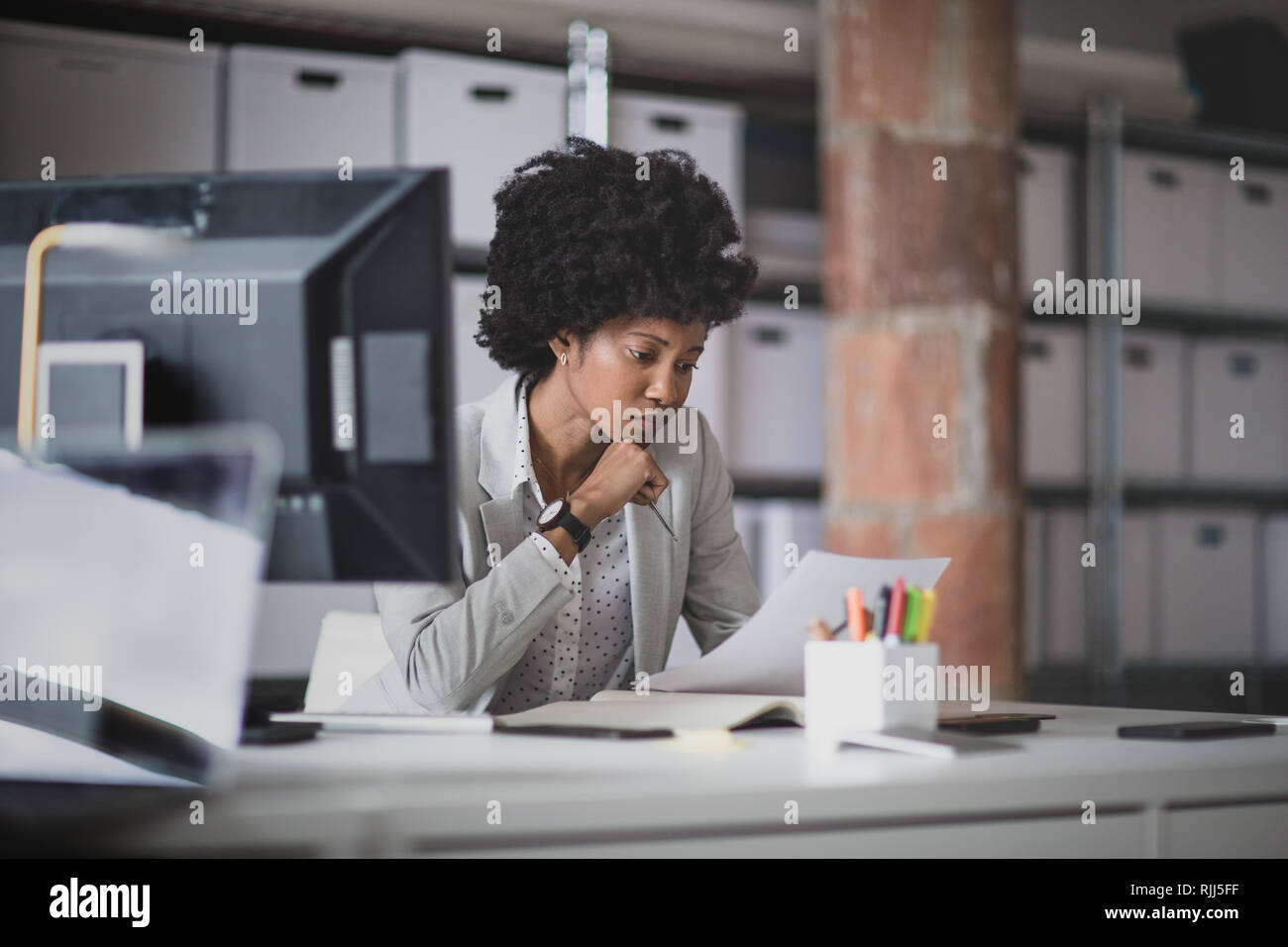 Femmina African American business executive lavora in un ufficio guardando la documentazione Foto Stock