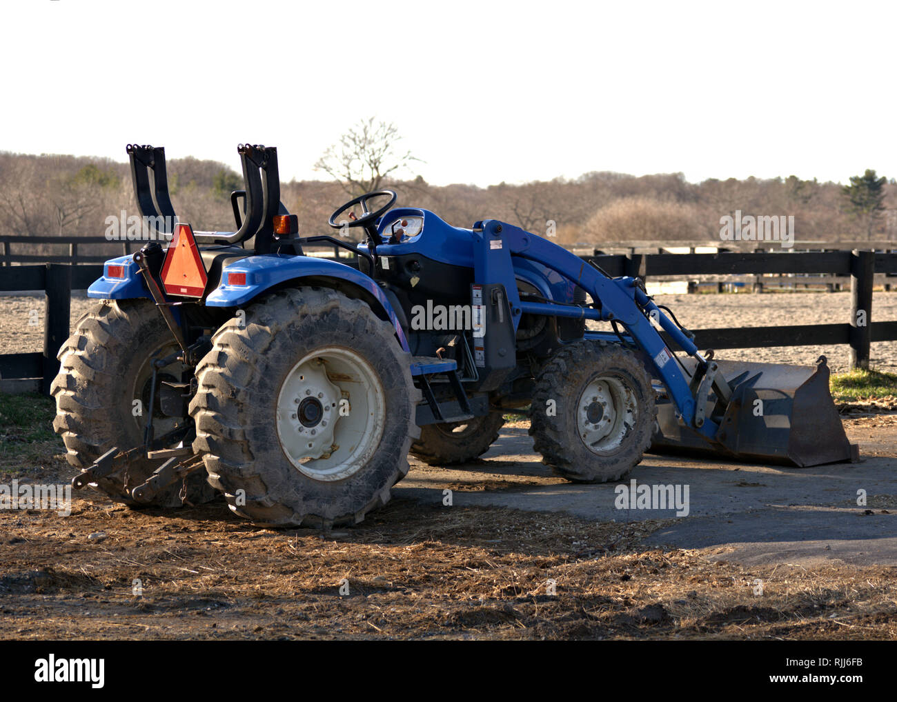 Una fattoria di blu il trattore è pronto per lavorare con i campi in background Foto Stock
