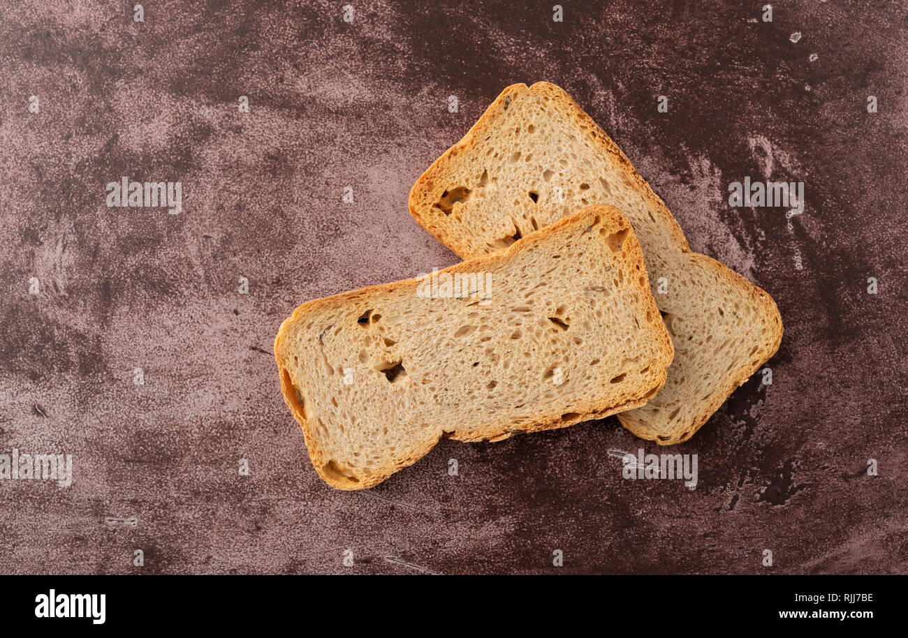 Vista dall'alto di due fette di segale Melba toast su uno sfondo marrone rossiccio illuminato con luce naturale. Foto Stock