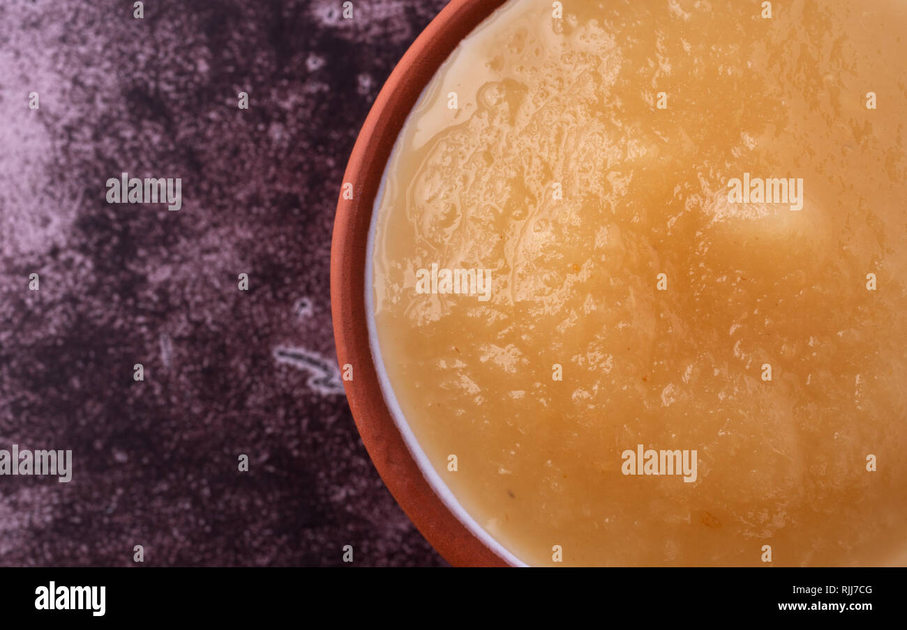 Tettuccio di chiudere la vista di una piccola ciotola riempita con zucchero libero di salsa di mele su uno sfondo marrone rossiccio. Foto Stock