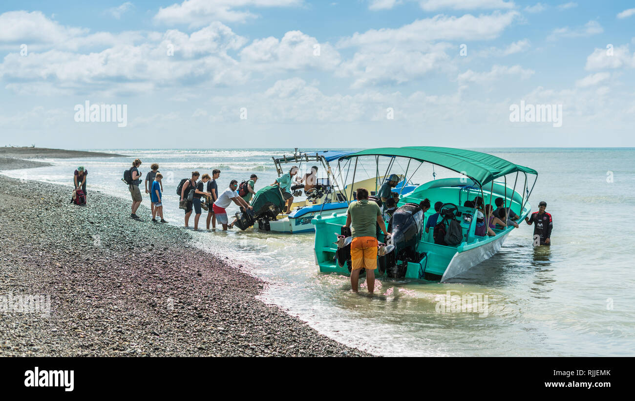 La foto di un gruppo di persone di salire a bordo delle imbarcazioni turistiche presso la splendida spiaggia vulcanica del Parco Nazionale di Corcovado, Costa Rica Foto Stock