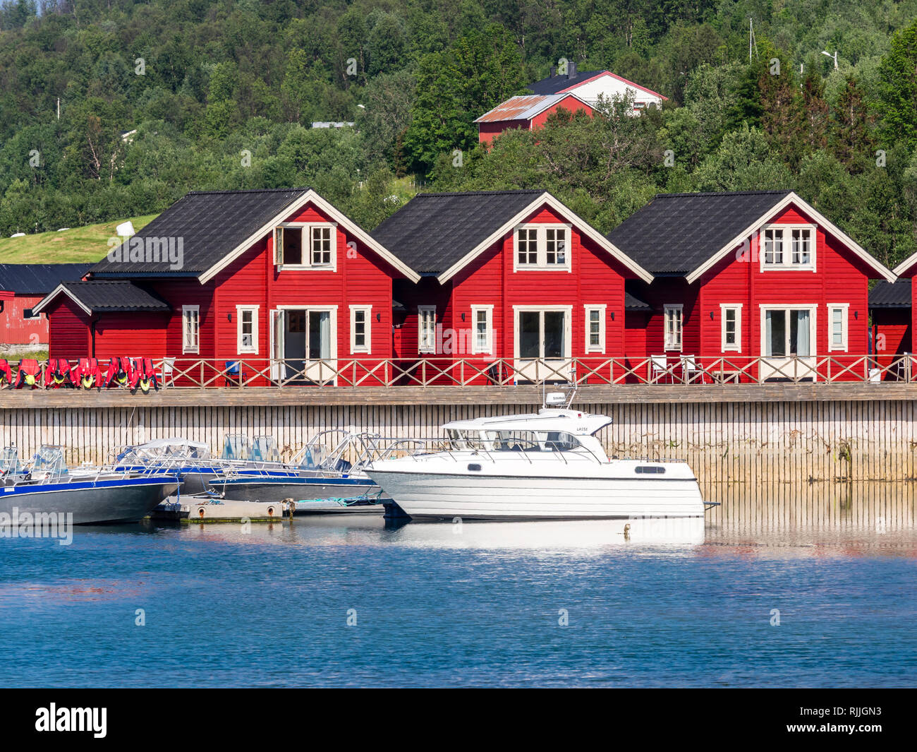 Tipico rosso-bianco in legno case vacanze, pier con barche da diporto, Lyngen,Lenangsstraumen, penisola di Lyngen Foto Stock